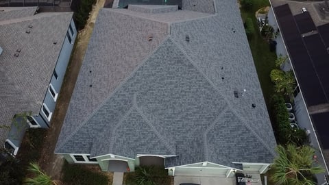 Aerial view of a residential roof with gray asphalt shingles and geometric diamond pattern design
